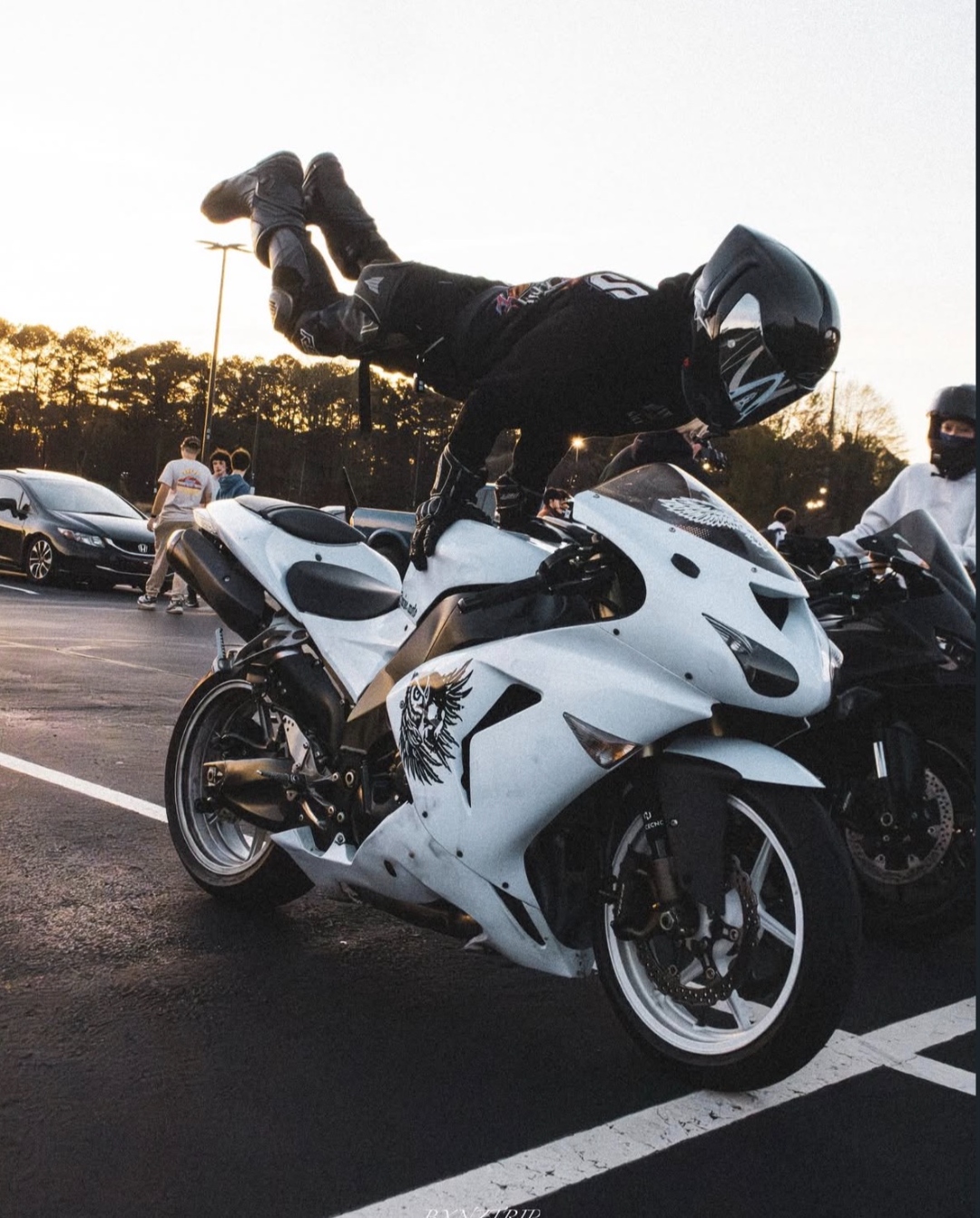 Stunt rider doing handstand on motorcycle at outdoor event